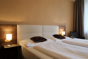 A hotel room with a large bed, two pillows, a nightstand with a lamp, and a chair. - Private Luxury Apartments (Frymburk)