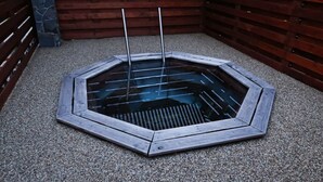 A hexagonal wooden structure with a central water feature and two poles. - Private Luxury Apartments (Frymburk)