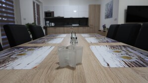 A dining table with placemats, a clear glass object, and a kitchen in the background. - Private Luxury Apartments (Frymburk)
