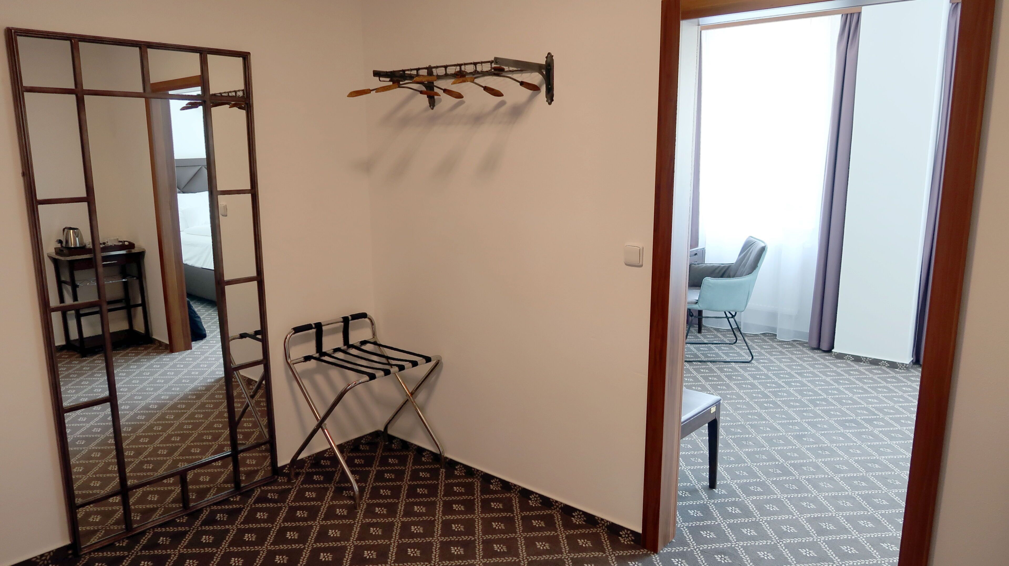 A room with a patterned floor, a metal drying rack, a chair, and a table with a chair.