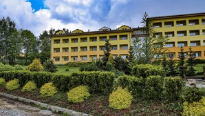 A multi-story yellow building with a flat roof, surrounded by well-maintained hedges and trees. - Private Luxury Apartments (Frymburk)