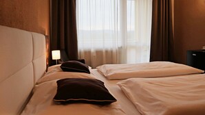 A hotel room with a bed, a nightstand, a lamp, and a view of the outdoors through sheer curtains. - Private Luxury Apartments (Frymburk)
