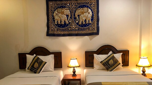 Two double beds with headboards, bedside tables with lamps, and a wall hanging above. - Ginis Beach Resort (Kamala)