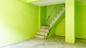 A staircase with a metal railing leading to a landing, surrounded by walls painted in a bright green color. - Tonrak Apartment (Hat Yai)