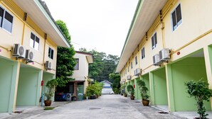 A row of two-story buildings with green doors and multiple air conditioning units. - Tonrak Apartment (Hat Yai)