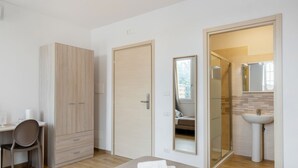 Une chambre à coucher comprenant un lit, un bureau, une armoire, une salle de bain avec un miroir et un lavabo.
