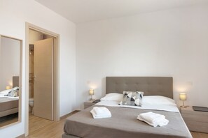 Een hotelkamer met een bed, nachtkastjes, een spiegel en een deur naar een badkamer.