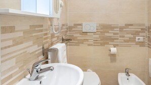 Un baño con lavamanos, inodoro, bidé y espejo.