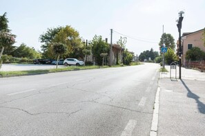 Een straat met geparkeerde auto's, een voetgangersoversteekplaats-bord en een lantaarnpaal.