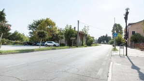 Una calle con coches aparcados, una señal de paso de peatones y un farol.