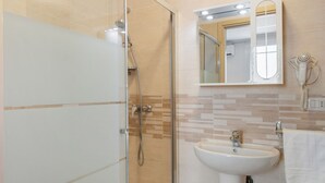 Une salle de bain moderne avec une douche à parois de verre, un lavabo blanc et un miroir au-dessus du lavabo.
