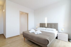 Een moderne hotelkamer met een groot bed, een nachtkastje en een deur.