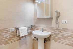 Een badkamer met een wastafel, handdoekrek, spiegel en haardroger.