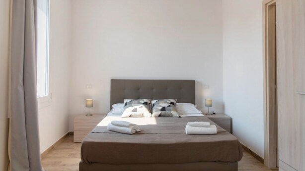 A hotel room with a large bed, two bedside tables with lamps, a window with curtains, and a wooden wardrobe. - Spacious room with private bathroom is part of the San Vincenzo Rooms Guest House and is perfect for 2 guests. The accommodation is located in the renovated building in Vigonza, which is 10 minutes by car from the center of Padua and on the direct route  (Vigonza)