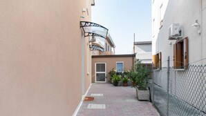 A narrow alleyway with a brick pathway, potted plants, a chain-link fence, and a building with a door and window. - Spacious room with private bathroom is part of the San Vincenzo Rooms Guest House and is perfect for 2 guests. The accommodation is located in the renovated building in Vigonza, which is 10 minutes by car from the center of Padua and on the direct route  (Vigonza)