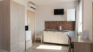 Une cuisine compacte équipée d’un micro-ondes, d’un évier, d’une chaise blanche et d’une petite table sur laquelle est posé un panneau.