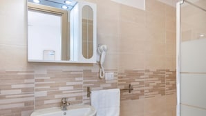 Une salle de bain équipée d’un lavabo, d’un miroir, d’un porte-serviettes et d’un sèche-cheveux.