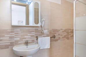 Une salle de bain équipée d’un lavabo, d’un miroir, d’un porte-serviettes et d’un sèche-cheveux.