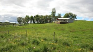 A house on a grassy hill with a fence in the foreground. - Eyvindartunga Farm Cottage (Bláskógabyggd)