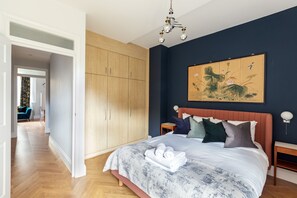 A bedroom with a large bed, wooden wardrobe, and a painting on the wall. - Beautiful 2 Bedroom Garden flat (London)