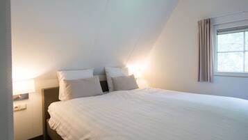 Quarto com cama, duas luminárias de cabeceira, janela com cortinas e uma tomada.