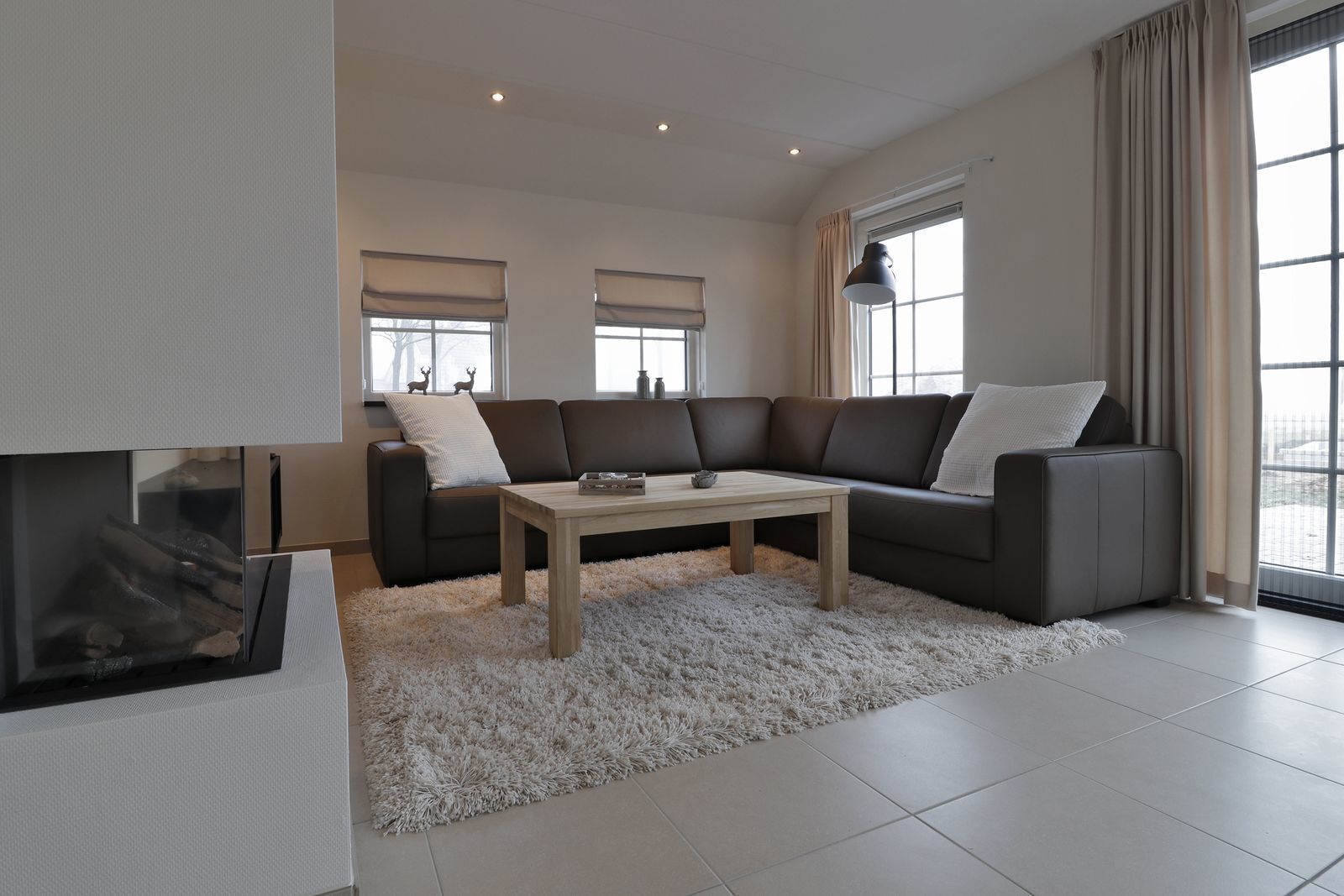 Een moderne woonkamer met een hoekbank, een houten salontafel en een open haard.