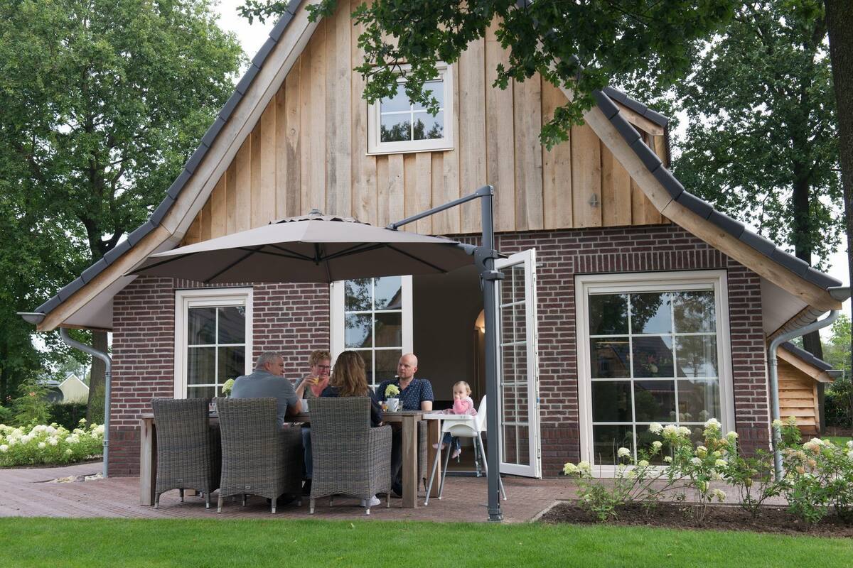 A wooden house with a brick exterior, a patio with wicker furniture, and a covered outdoor seating area.