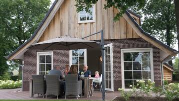 A wooden house with a brick exterior, a patio with wicker furniture, and a covered outdoor seating area.
