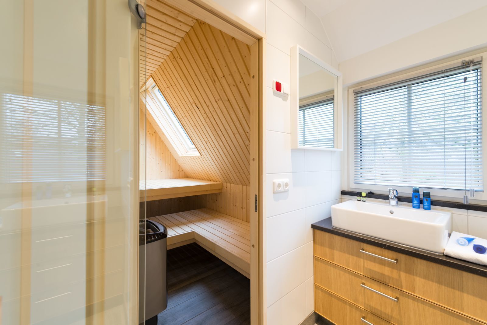 A modern bathroom with a skylight, a large sink, and wooden cabinetry.