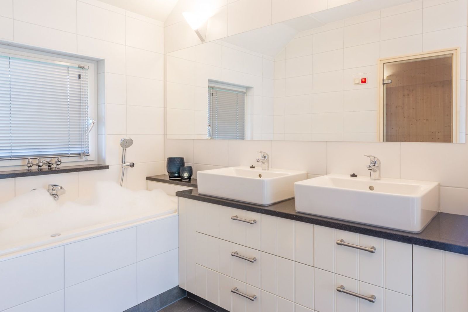 Ein modernes Badezimmer mit einer Badewanne, zwei Waschbecken und einem großen Spiegel.