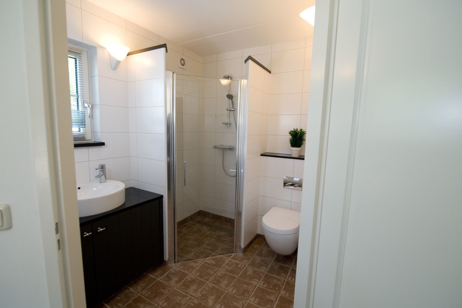 A modern bathroom with a shower, toilet, and sink.