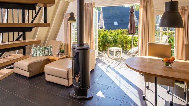 Una sala de estar moderna con chimenea, una escalera y vista al jardín trasero.