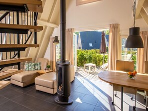 Una sala de estar moderna con chimenea, una escalera y vista al jardín trasero.