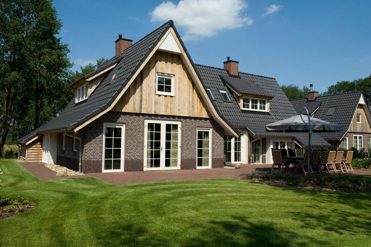 A large, two-story house with a sloped roof, brick exterior, and a well-maintained lawn.