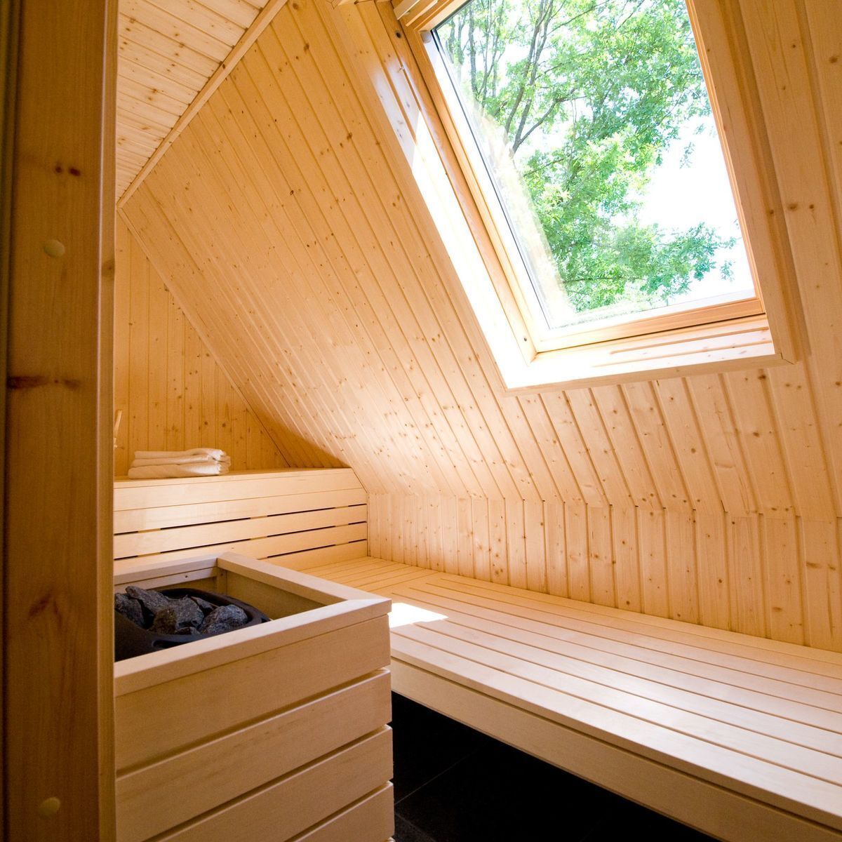 Eine Holzsauna mit schrägem Dach und Oberlicht, ausgestattet mit einer Sitzbank und einer Aufbewahrungsbox.