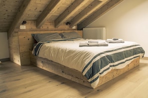 A wooden bed with a striped blanket, a pillow, and folded towels. - Casa Ekharle - Guesthouse (Rotzo)
