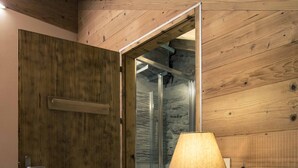 Een kamer met houten lambrisering, een bed, een nachtkastje en een deur naar een badkamer.