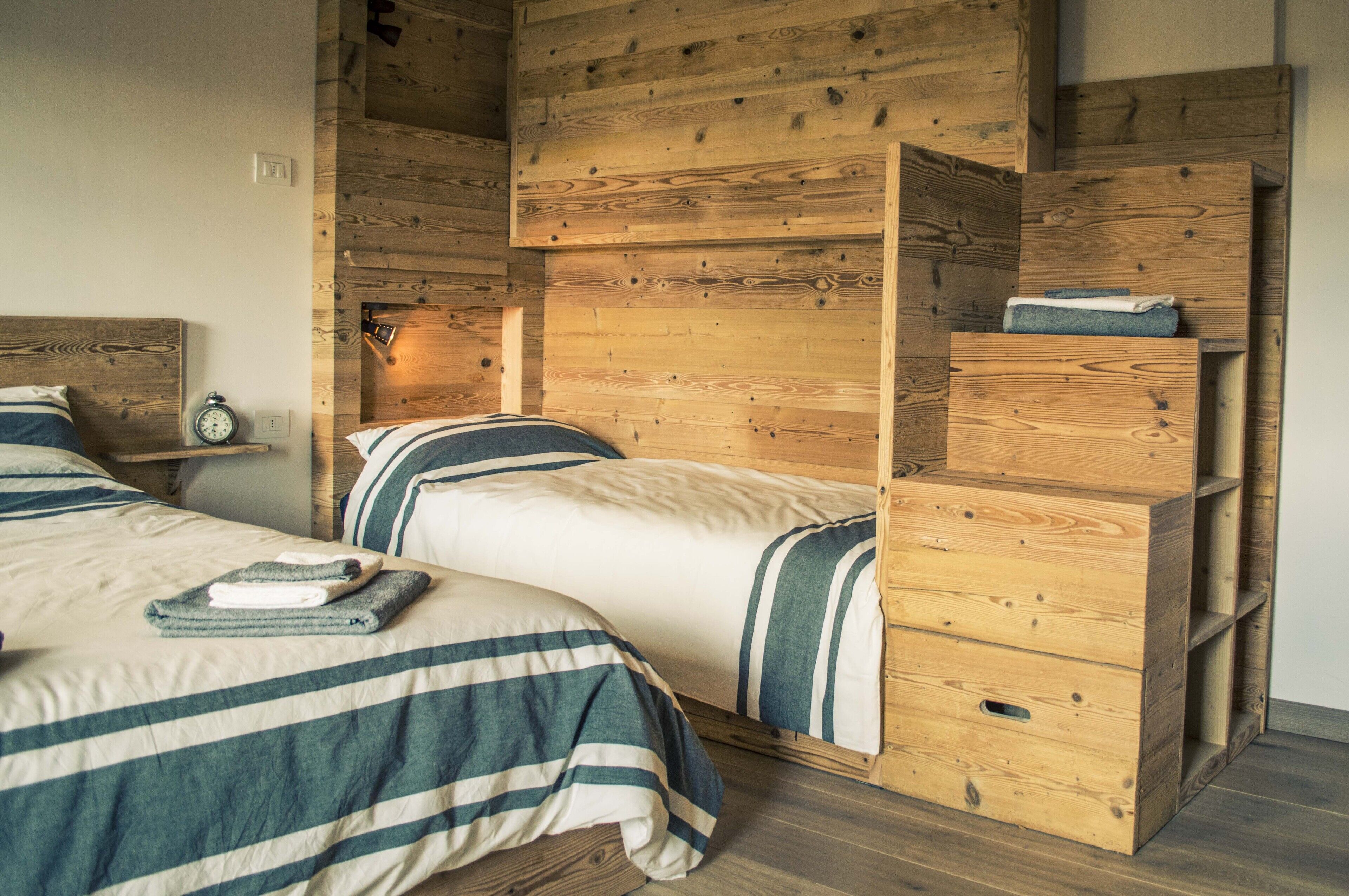 Una habitación con dos camas, cabeceros de madera y muebles de almacenaje integrados de madera.