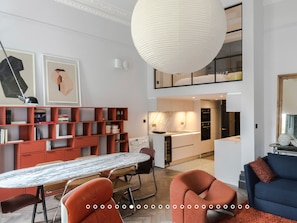 A modern living room with a dining area, a kitchen, and a loft bedroom. - The Bengal Tiger: 2 bd apt rich with character (London)