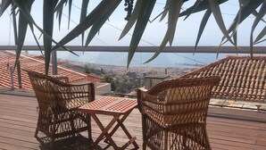 A terrace with wicker furniture and a table, overlooking a cityscape. - Old kitchen Cus cus factory Villa with pool and sea view (Funchal)
