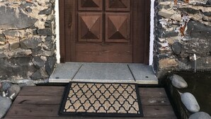 A stone wall with a wooden door featuring geometric cutouts. - Old kitchen Cus cus factory Villa with pool and sea view (Funchal)