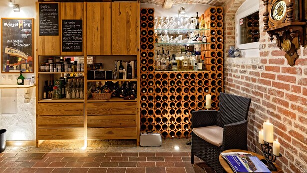 Un interior acogedor con estanterías de madera, un botellero y un sillón de mimbre.