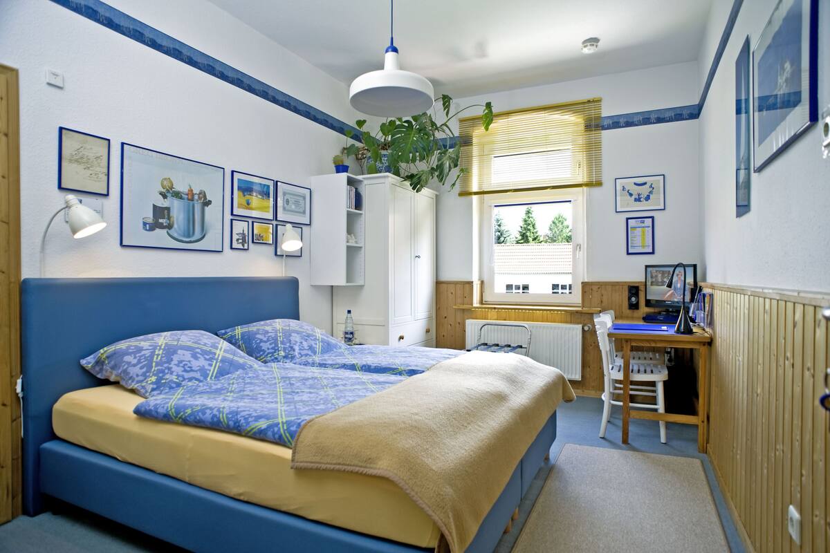 A bedroom with a bed, desk, and window.
