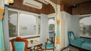 A room with a view of a body of water, a wooden ceiling, and a sofa. - Jheel Hotel and Restaurent (Udaipur)
