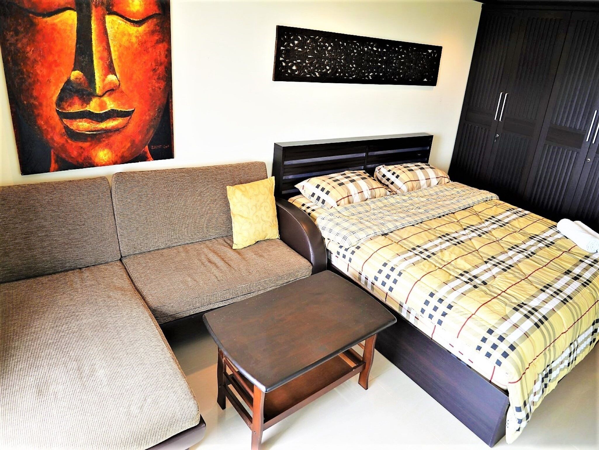 Un dormitorio con cama, sofá, una mesita y una obra de arte en la pared.