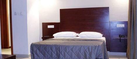 A standard hotel room with a bed, nightstand, and a dresser.