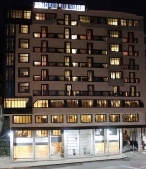 Un hotel de varios pisos con ventanas iluminadas y un letrero que dice "HOTEL DU NORD".