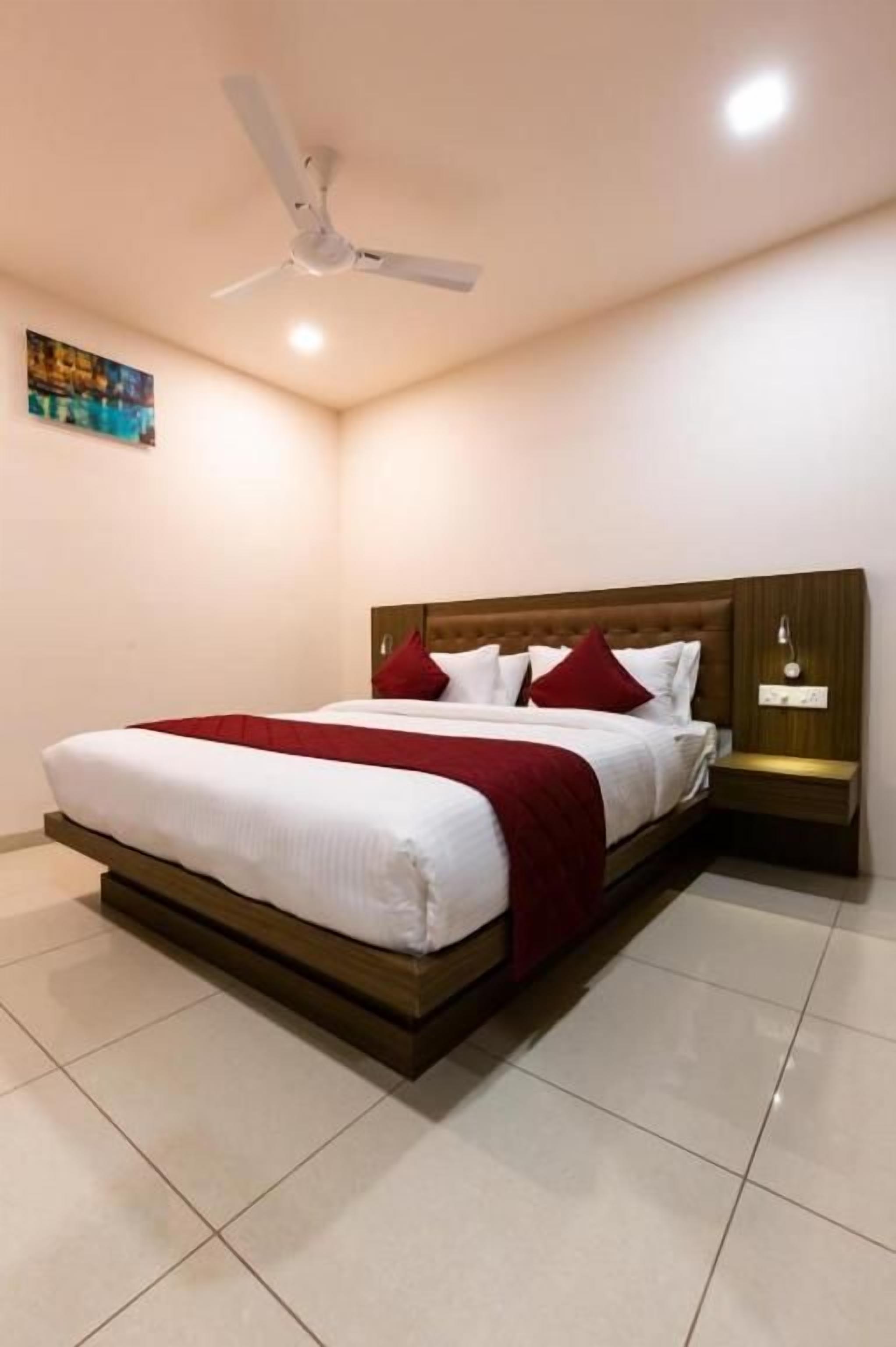 A bedroom with a bed, a nightstand, a ceiling fan, and a wall-mounted light fixture.