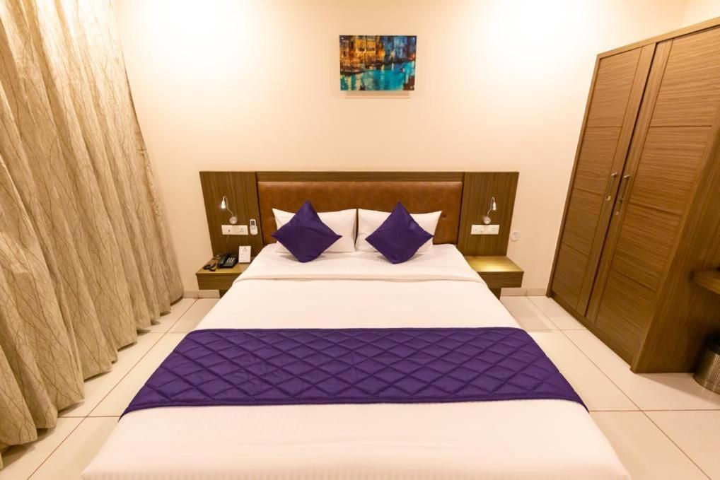 A hotel room with a large bed, two nightstands, a wooden wardrobe, and a painting on the wall.