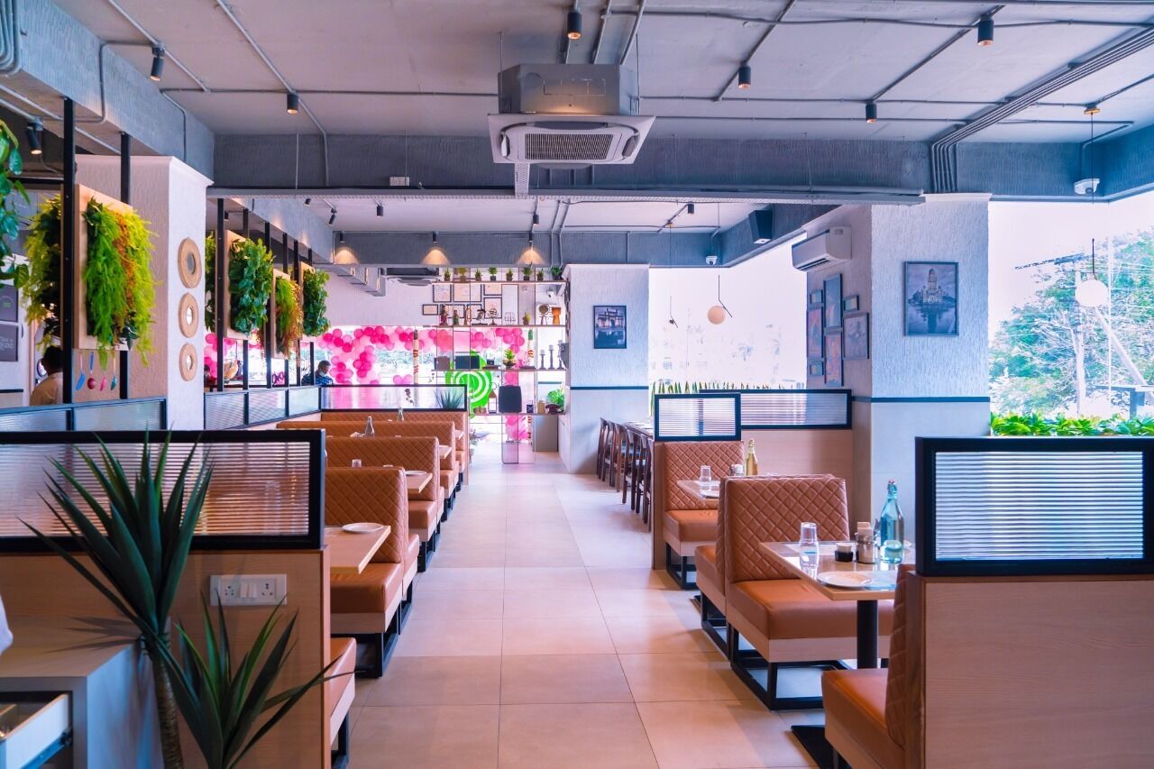 Ein modernes Restaurant mit Sitzecken und Tischen, einem hellen Innenraum und Blick ins Freie.